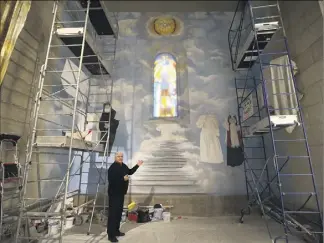  ?? (Photo Sébastien Botella) ?? Le père Gil Florini devant l’imposant chantier de la fresque en cours de réalisatio­n, dans l’un des espaces libres de l’église Saint-Pierre d’Arène. L’église va recevoir de nouveaux saints…