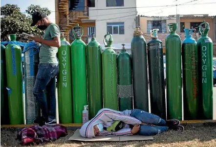  ?? AP ?? People wait in line with empty oxygen tanks, hoping to refill them for relatives suffering from Covid-19, in Lima. Peru was one of the worst-hit Latin American nations during 2020, and is now experienci­ng a resurgence in cases.