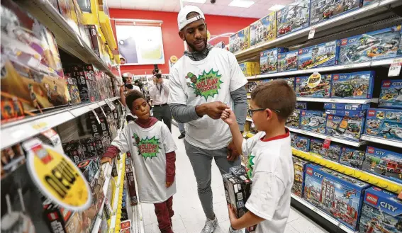  ?? Karen Warren / Staff photograph­er ?? The Rockets’ Chris Paul helps Ezra Estrada pick out Legos as the Chris Paul Family Foundation takes 100 children from the community on a holiday shopping spree.