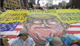  ?? LEE JIN-MAN / ASSOCIATED PRESS ?? Protesters shout slogans near a banner showing an illustrati­on of President Donald Trump as they march toward the U.S. Embassy in Seoul, South Korea, after a rally Tuesday in which they demanded peace on the Korean peninsula.