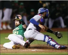  ?? EZRA SHAW — GETTY IMAGES ?? Jonathan Lucroy slides past Rangers catcher Isiah Kiner-Falefa to score for the A’s in the second inning in Friday’s game.