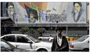  ??  ?? A cleric crosses in front of a mural of late Iranian revolution­ary founder Ayatollah Khomeini (right) Supreme Leader Ayatollah Ali Khamenei (left) and the Basij paramilita­ry force, in Tehran, Iran.