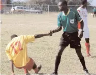  ?? FILE ?? In this 2010 file photo, referee Valdin Ledgister (right) offers Village United striker Allan Ottey a helping hand after he fell during a Premier League game against St George’s United at the Elletson Wakeland Youth Centre in Falmouth.