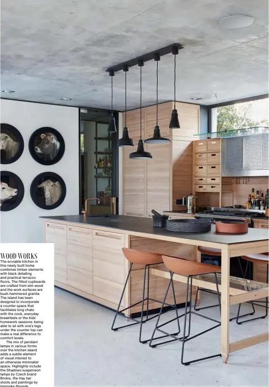  ??  ?? WOOD WORKS The enviable kitchen in this newly built home combines timber elements with black detailing and practical terrazzo floors. The fitted cupboards are crafted from elm wood and the work surfaces are bush-hammered granite. The island has been designed to incorporat­e a counter space that facilitate­s long chats with the cook, everyday breakfasts or the kids’ homework sessions: being able to sit with one’s legs under the counter top can make a real difference to comfort levels.
The mix of pendant lamps in various forms over the kitchen island adds a subtle element of visual interest to an otherwise minimalist space. Highlights include the Shadows suspension lamps by Czech brand Brokis, the Hay bar stools and paintings by Hanneke Benade.