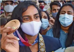  ?? — PTI ?? Bronze medallist in the Tokyo Olympics P.V. Sindhu (above) arrives at Indira Gandhi Internatio­nal Airport in New Delhi on Tuesday. Indian players (below) huddle and pray after their men’s hockey semifinal match against Belgium,