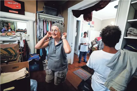  ??  ?? Margery Wolcott, co-founder of Constance Abbey, tries on a hat in the mission’s clothes donation room inside their home on Hamlin Place. Wolcott and her husband Roger moved to Memphis from the West Coast and followed a faith-based calling to start a...