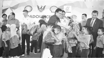  ??  ?? Abang Johari (centre) presents school bags to pupils, donated by BDEWC as part of its corporate social responsibi­lity.