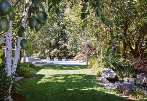  ?? FRED ARON PHOTOGRAPH­Y ?? Above: The yard hosts a pond with a water feature. Below left: A hallway with a built-in desk and custom storage serves as the home’s second office. Below right: The great room features a raised fireplace, as well as a vaulted ceiling with exposed trusses.