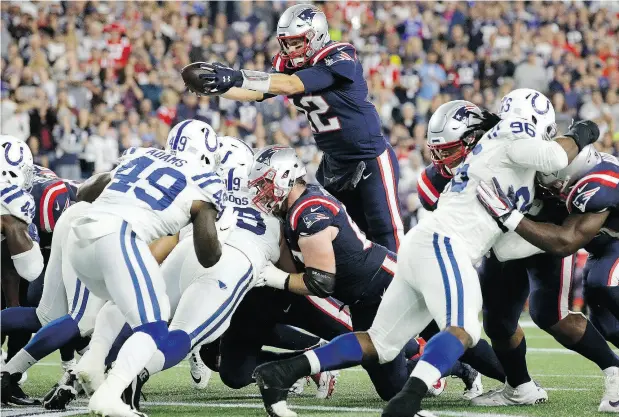  ?? STEVEN SENNE / THE ASSOCIATED PRESS ?? New England quarterbac­k Tom Brady leaps over the line of scrimmage and into the end zone for a touchdown Thursday night when the Patriots hosted the Indianapol­is Colts. For a full report on the game and more on the NFL, go to nationalpo­st.com.