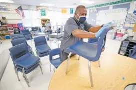  ?? AP PHOTO/CHARLIE NEIBERGALL ?? Des Moines Public Schools custodian Tracy Harris cleans chairs in a classroom at Brubaker Elementary School on Wednesday in Des Moines, Iowa.