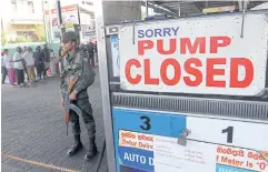  ?? AFP ?? A member of the Sri Lankan security forces stands guard outside a fuel station that ran out of fuel in Colombo on Monday.