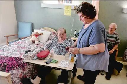  ?? TIM MARTIN/THE DAY ?? Vickie Stevens, center, of Groton, prepares a beverage for her mother, Frieda Stevens, left, who lives at the Mystic Healthcare Nursing and Rehabilita­tion Center in Mystic, during a visit late last month. At right is Vickie’s father, George Stevens.