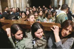  ?? GIL COHEN-MAGEN/GETTY-AFP ?? Palestinia­n Arab scouts help carry a wooden cross out of the Church of the Holy Sepulcher during the Good Friday procession in Jerusalem’s Old City.