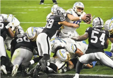  ?? Chris Unger / Getty Images ?? Chargers quarterbac­k Justin Herbert reaches for the end zone on the last play of Los Angeles’ overtime victory against Las Vegas, which had taken the lead with a Daniel Carson field goal earlier in extra time.