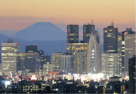  ?? KAZUHIRO NOGI/Getty Images ?? Tokyo sparkles as Mount Fuji rises up behind the skyline. The city’s Ginza shopping district is among the top attraction­s.