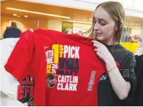  ?? AP PHOTO/MICHAEL CONROY ?? Shelby Tekulve, 20, displays one of the Caitlin Clark shirts she was purchasing Tuesday in the Indiana Fever team store in Indianapol­is.