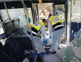  ?? Sebastian Scheiner Associated Press ?? ISRAELI emergency workers transport the body of a Palestinia­n after a bus attack in Jerusalem that left two passengers and one Palestinia­n assailant dead.