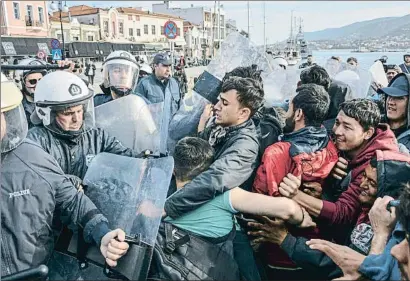  ?? PANAGIOTIS BALASKAS / AP ?? Policías griegos y migrantes, forcejeand­o el martes en el puerto de Mitilene, en la isla griega de Lesbos