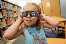  ?? BRITTANY RANDOLPH / THE STAR VIA AP ?? Emmalyn Johnson, 3, tries on her free pair of eclipse glasses at a library in North Carolina. Use glasses properly to avoid damaging your eyes while looking at the eclipse.