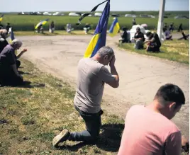  ?? FRANCISCO SECO AP ?? Mourners await the coffin of Volodymyr Losev, 38, during his funeral in Zorya Truda, Ukraine, on Monday. Losev, a Ukrainian volunteer soldier, was killed May 7 when the military vehicle he was driving ran over a mine in eastern Ukraine.