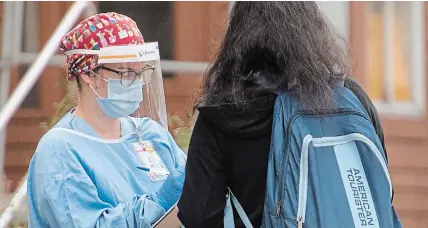  ?? GRAHAM HUGHES THE CANADIAN PRESS ?? A health-care worker takes a woman’s details at a COVID-19 testing clinic in Montreal, Sunday as the COVID-19 pandemic continues in Canada and around the world. Quebec had almost 900 new cases Sunday, while Ontario had almost 500.