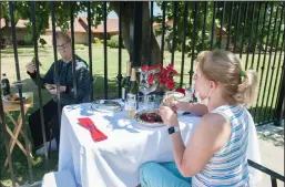  ??  ?? Susan Webb of Forest Hill, foreground, has a picnic through the fence as she visits her sister, Kim Clayworth, where she lives at the Hanot Foundation in Lockeford on Friday.