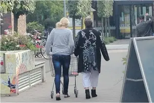  ??  ?? A resident at De Hogeweyk Dementia Village walks toward the supermarke­t. The village is modelled after the open- minded societal values of The Netherland­s.