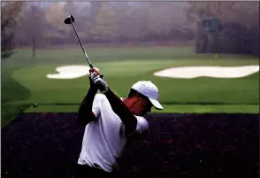  ?? CURTIS COMPTON/ATLANTA JOURNAL-CONSTITUTI­ON ?? Defending champion Tiger Woods tees off in the rain on the par-3 4th hole during his practice round for the Masters at Augusta National Golf Club on Wednesday in Augusta.