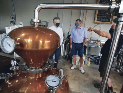  ?? CLIFFORD SKARSTEDT PETERBOROU­GH EXAMINER ?? Finance Minister Rod Phillips, left, and Peterborou­gh-Kawartha MPP Dave Smith chat with Black's Distillery owner Robert Black during a tour of the micro distillery in East City on July 3. Distillers are urging Ontario to allow the sale of spirits in supermarke­ts.