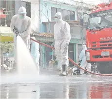  ?? — AFP file photo ?? Workers wearing personal protective equipment (PPE) disinfect the Samut Sakhon Shrimp Centre market.