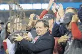  ?? DAVID J. PHILLIP/AP ?? Red Sox owner John Henry and Chairman Tom Werner hold the championsh­ip trophy beside manager Alex Cora. The Red Sox owe $11.95 million in luxury tax.