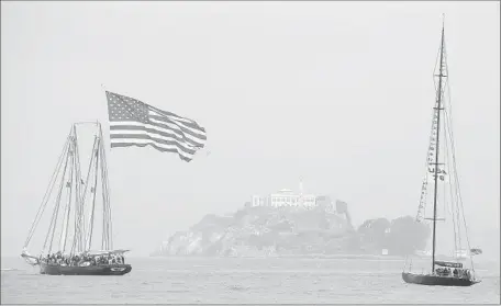  ?? Eric Risberg Associated Press ?? THE YACHT
America, left, and USA 76 make their way past Alcatraz Island during a parade of boats for the America’s Cup in San Francisco. The city had been expecting to reap $1.4 billion in economic activity by hosting the race, but things haven’t gone...