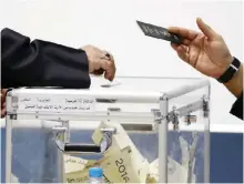  ??  ?? A close up shot shows the hand of a Kuwaiti man casting his vote for the parliament­ary elections at a polling station.