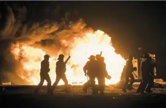  ?? Christophe­r Furlong/Getty Images ?? French riot police advance through tear gas and smoke from a fire to disperse migrants throwing stones and lighting fires at the Jungle migrant camp Sunday in Calais, France. Volunteers and officials have began distributi­ng informatio­n to migrants as...