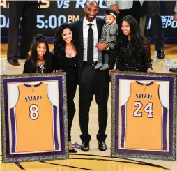  ?? (Reuters) ?? LOS ANGELES LAKERS icon Kobe Bryant (center) and his family pose for a photo during a halftime ceremony at Staples Center on Monday night to retire the two uniform numbers Bryant wore during his 20-year career. The visiting Golden State Warriors beat...