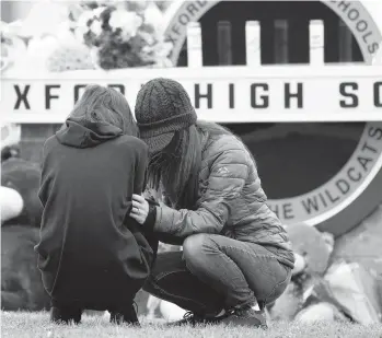  ?? PAUL SANCYA/AP ?? Mourners share their grief Wednesday at a makeshift memorial at Oxford High School in Michigan. Oakland County authoritie­s did not reveal a motive in the shooting.