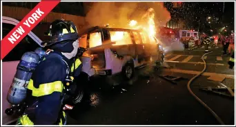  ??  ?? Firefighte­rs tackle the blaze on a police van let alight by furious protesters