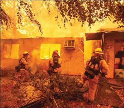  ??  ?? Firefighte­rs push down a wall while battling against a wildfire that gutted a apartment complex in Paradise, north of Sacramento.