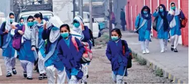  ?? File / Agence France-presse ?? ↑
Students, wearing face masks, arrive at a school in Lahore.
