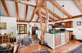  ?? ?? The living area and kitchen, above, with cherry trees providing part of the support structure; one of four bedrooms, left; the living space and wood stove, below. At far left is a cabin on the property.