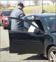  ?? EVAN BRANDT — MEDIANEWS GROUP ?? Pottstown Schools employees Mary Ellen Urguhart and Dave Livengood hand off five days worth of food the fastmoving car line at Lincoln Elementary School Wednesday.