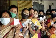  ?? PTI ?? Women show their voter ID cards as they stand in a queue, at Ranaghat, Nadia, on Saturday