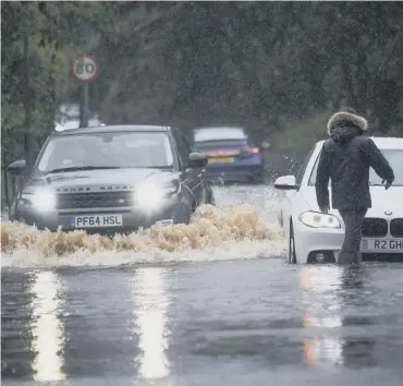  ??  ?? 0 Cars make their way through flood water following torrential rain