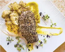  ??  ?? “Everything” Crusted Salmon has apricot couscous, fried cauliflowe­r, cumin scented yogurt, curry mustard and surrounded by Hull Valley Farms microgreen­s Thursday at SURV in Forks Township..