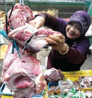  ?? HANUNG HAMBARA/JAWA POS ?? TERAMPIL DENGAN PISAU: Astuti memotong daging sapi sesuai permintaan pembeli di Pasar Larangan kemarin.