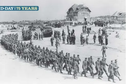  ??  ?? German troops march on the beach at Bernières-sur-Mer, France, after being captured by Canadians during the D-Day assault.