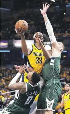  ?? ?? Myles Turner, de los Pacers, recibe una falta de Damian Lillard, de los Bucks, junto al centro Brook Lopez.