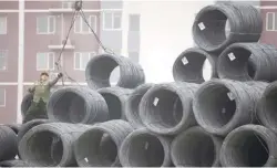  ??  ?? A worker handling coils of steel wire at a steel wholesale market in Beijing, China.