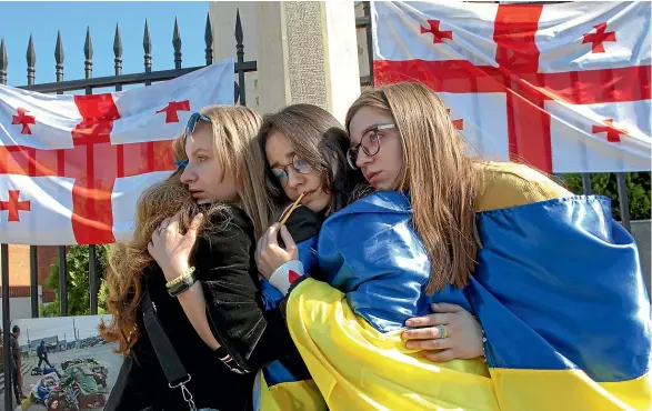  ?? AP ?? Young Georgian protesters draped in Ukrainian flags take part in a demonstrat­ion outside Ukraine’s embassy in Tbilisi. The Georgian government’s cautious reaction to the Russian invasion, including refusing to impose sanctions, is at odds with the public mood in a country that was itself invaded by Russia in 2008 and ended up losing 20% of its territory to its belligeren­t neighbour.