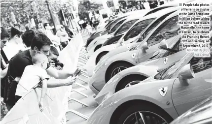  ??  ?? People take photos of Ferraris on display at the Corso Sempione in Milan before taking the to the road toward Maranello, the home of Ferrari, to celebrate the Prancing Horse’s 70th anniversar­y, on September 8, 2017.